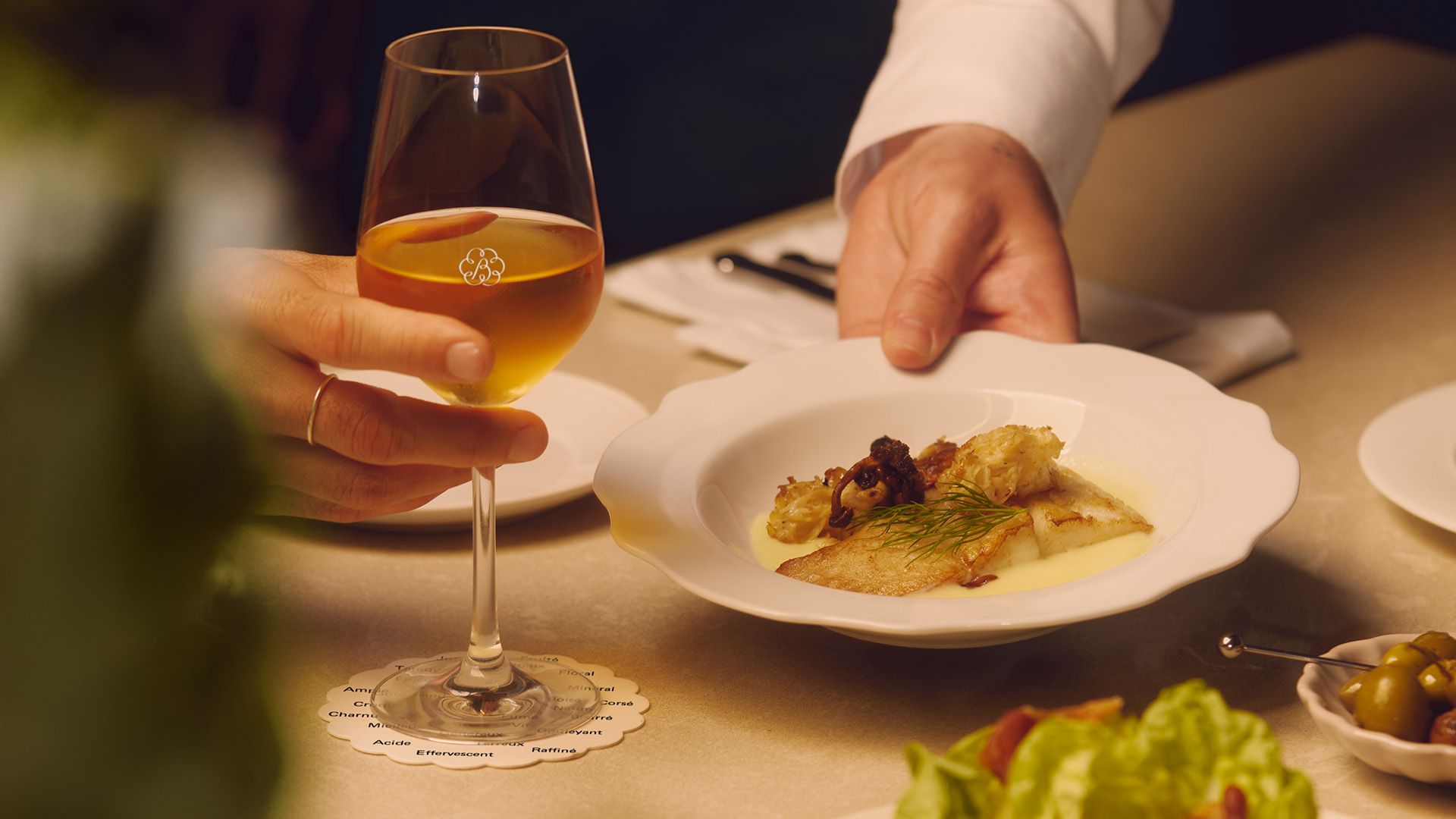 Main d’un serveur qui dépose une assiette sur une table.