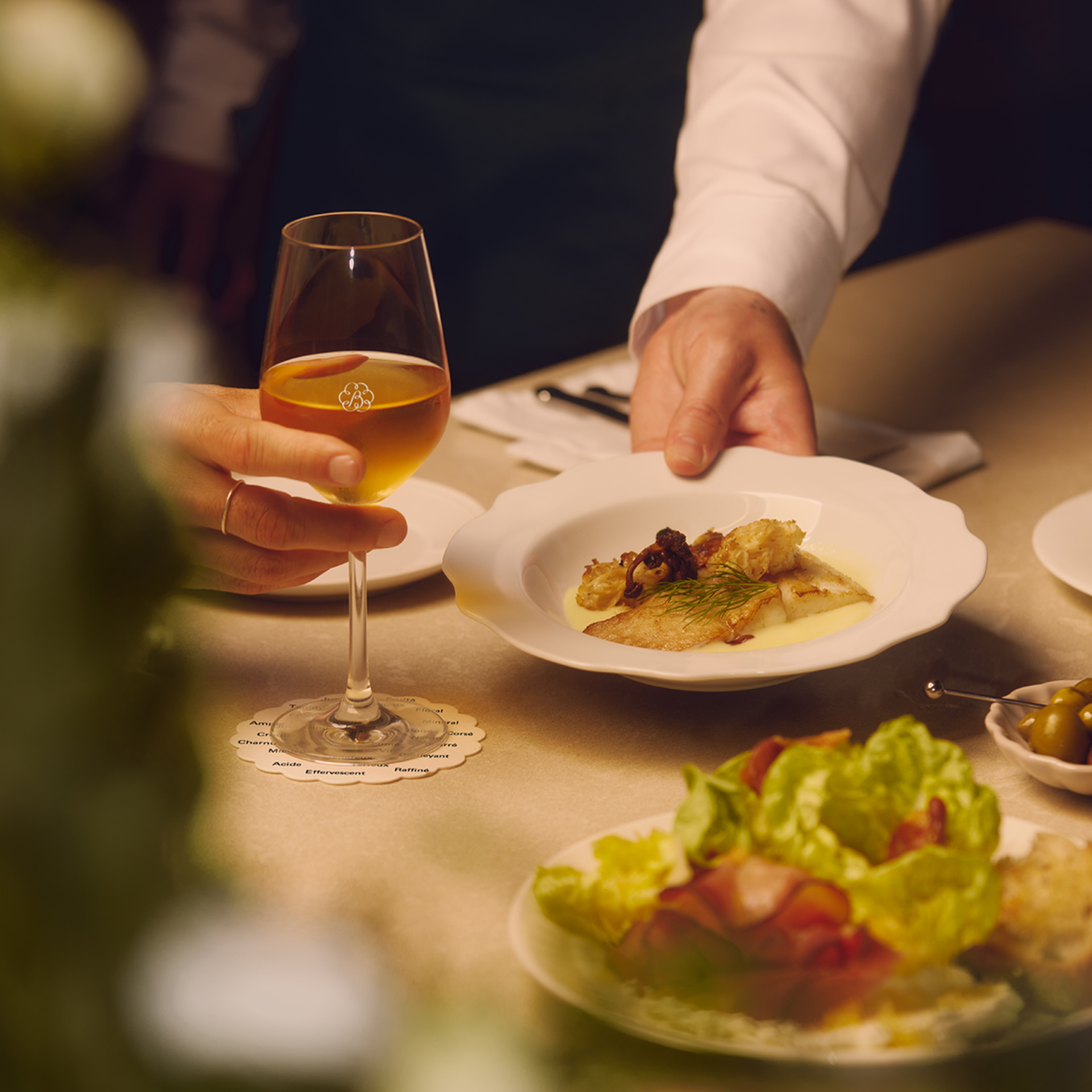 Main d’un serveur qui dépose une assiette sur une table.